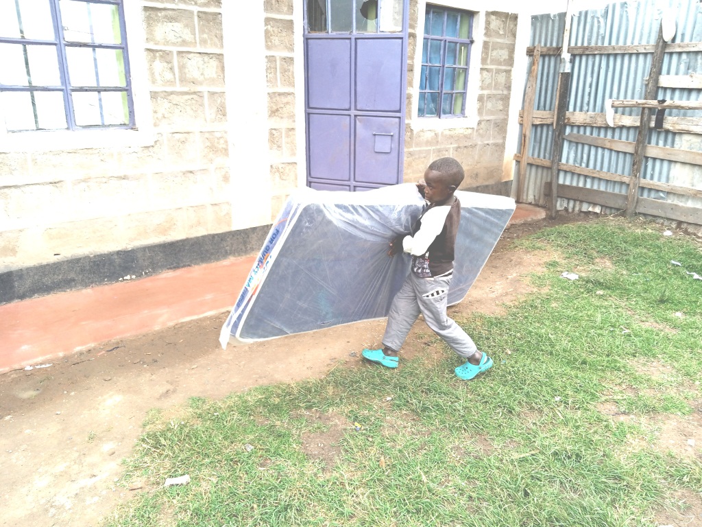 Kamau (YOU.REP kid) carrying a mattress
