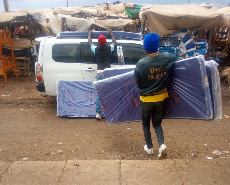 The shop attendants loading the mattress on the car